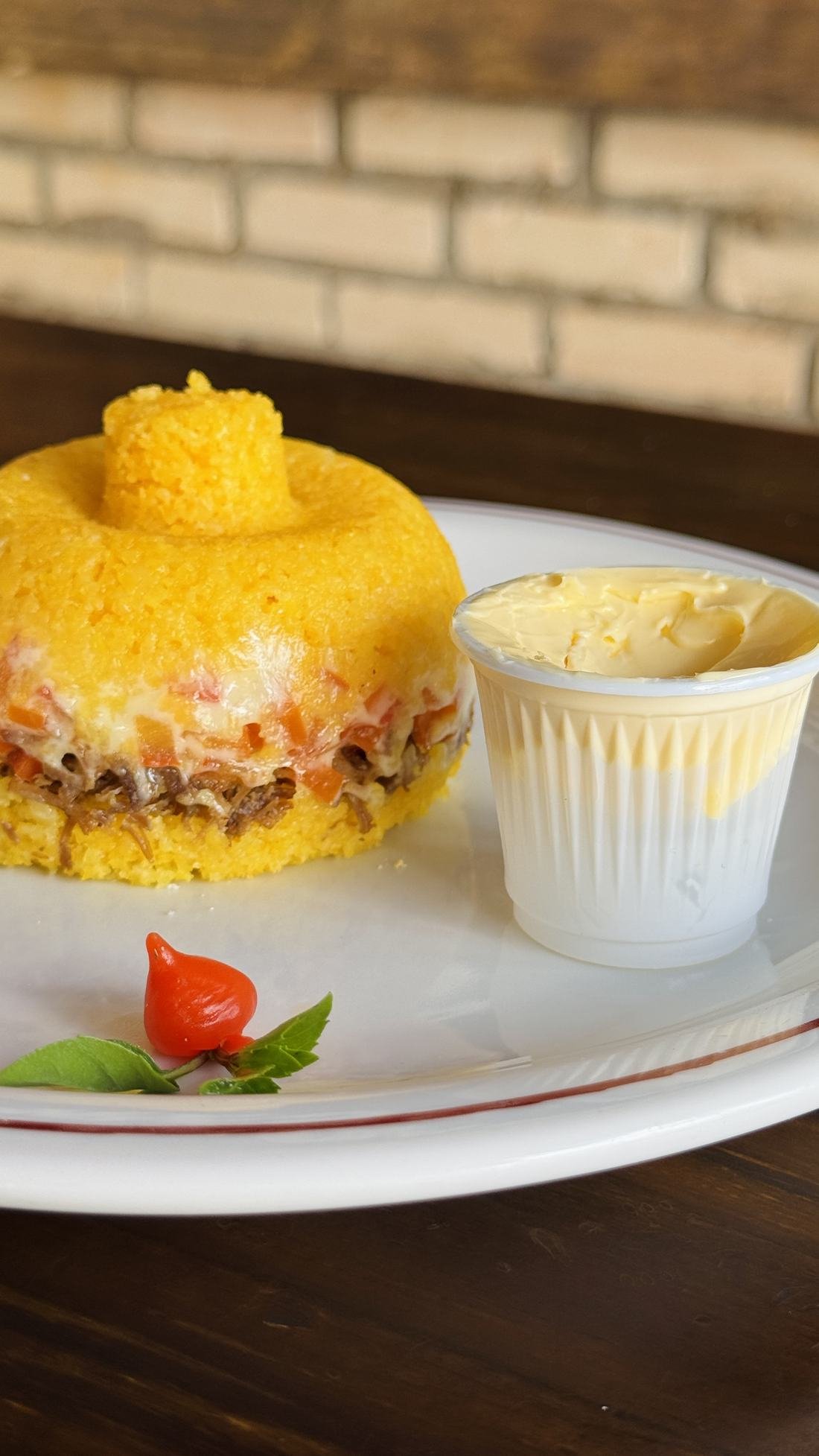 Prato de milho com carne e queijo, servido com manteiga da terra